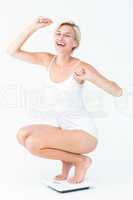 Happy attractive woman crouching on a scales