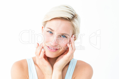 Happy blonde smiling at camera with hands on cheeks