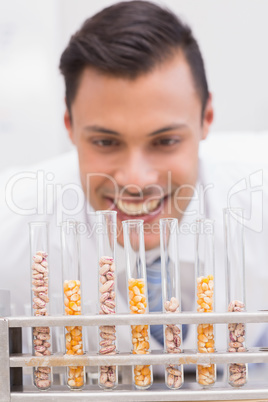 Happy scientist looking at tubes of corn and kernel
