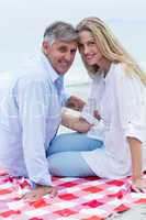 Happy couple sitting on a blanket and smiling at camera