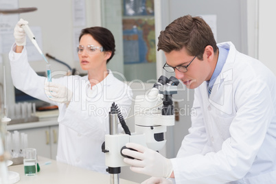 Scientists working with microscope and test tube