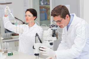 Scientists working with microscope and test tube