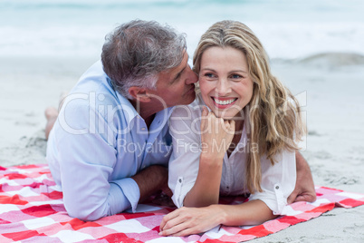 Happy couple lying on a blanket and kissing