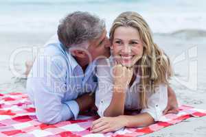 Happy couple lying on a blanket and kissing