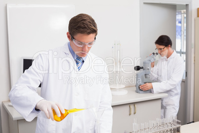 Scientists working attentively with test tube and microscope