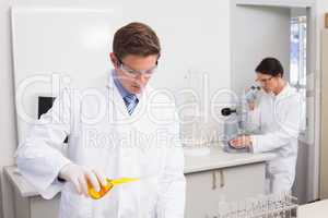 Scientists working attentively with test tube and microscope