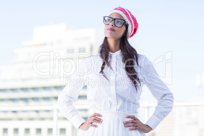 Thoughtful brunette looking up with hands on hips