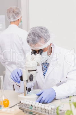 Scientists examining tubes with microscope
