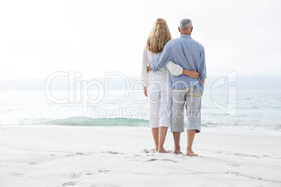 Happy couple hugging each other and looking at the sea