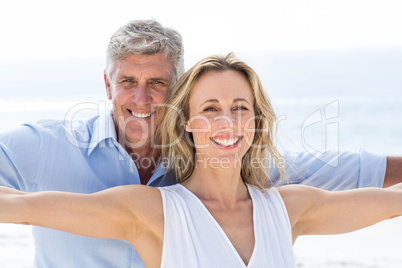 Happy couple standing by the sea arms outstretched