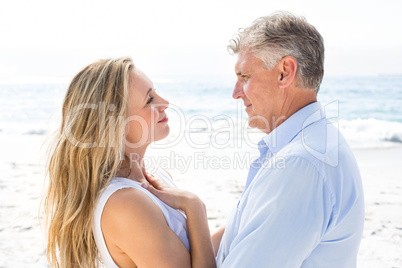 Happy couple standing by the sea and smiling at each other