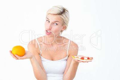 Pretty woman deciding between pizza and an orange