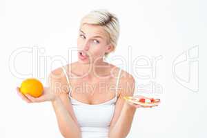 Pretty woman deciding between pizza and an orange