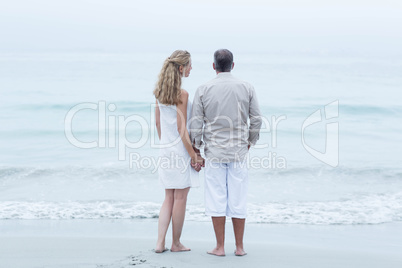 Happy couple standing by the sea and holding hands