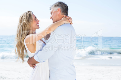 Happy couple smiling at each other by the sea