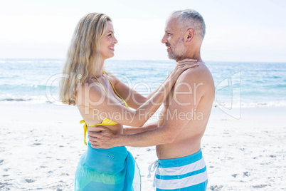 Happy couple standing by the sea and smiling at each other