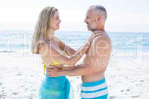 Happy couple standing by the sea and smiling at each other