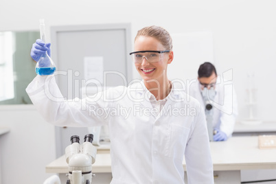 Scientist examining blue precipitate in baker