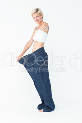 Blonde wearing too large pants with the thumb up