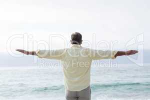 Thoughtful man standing by the sea arms outstretched