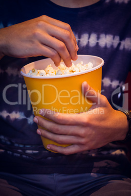 Young man watching a film and eating pop corn