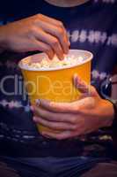 Young man watching a film and eating pop corn