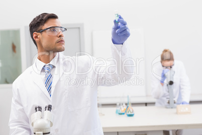 Scientist examining blue precipitate in tube