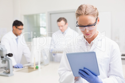 Scientist using tablet while colleagues working behind