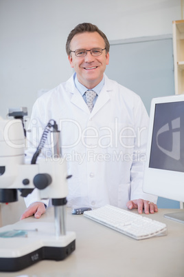 Happy scientist looking at camera with hands on table