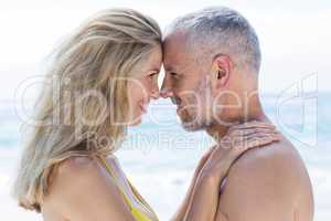 Happy couple standing by the sea and smiling at each other