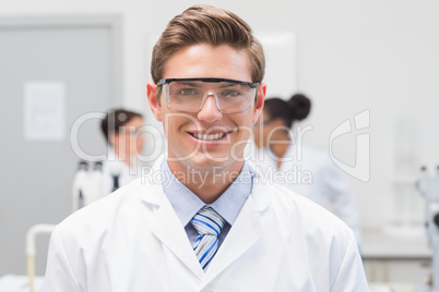 Happy scientist smiling at camera with protective glasses