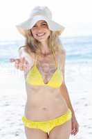 Smiling pretty blonde in bikini offering her hand