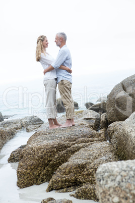 Happy couple standing on the rock and looking at each other