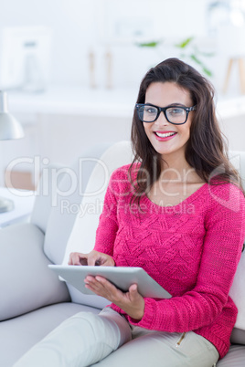 Smiling beautiful brunette using her tablet on the couch