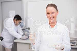 Smiling scientist filling a petri dish