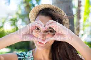 Smiling beautiful brunette doing heart shape with her hands