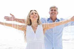 Happy couple standing by the sea arms outstretched