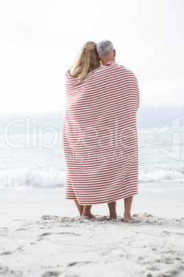 Happy couple hugging each other and looking at the sea with blan