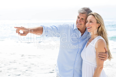 Happy couple standing by the sea and pointing something