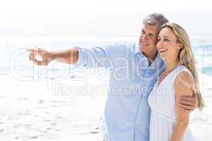 Happy couple standing by the sea and pointing something