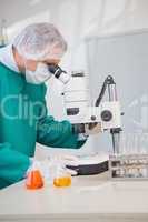 Scientist in scrubs using microscope