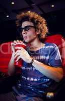 Young man watching a 3d film and drinking soda