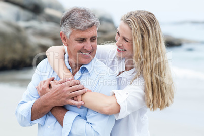 Happy couple hugging each other by the sea