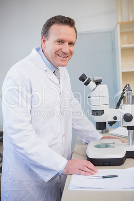 Smiling scientist examining sample with microscope