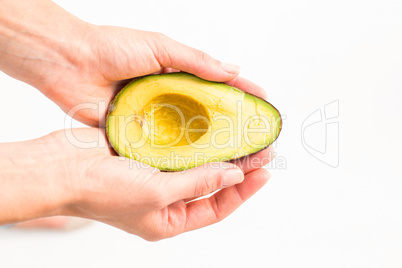 Woman presenting half of an avocado