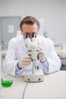 Scientist examining petri dish with microscope