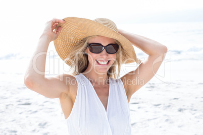 Smiling blonde in white dress wearing sun glasses and straw hat
