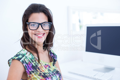 Smiling beautiful brunette sitting in front of her computer