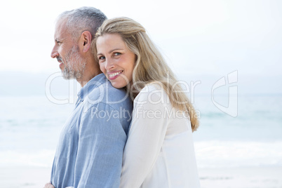 Happy couple hugging each other and looking at the sea