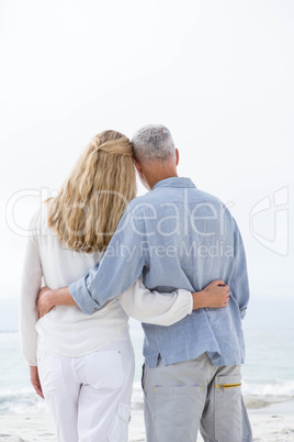 Happy couple hugging each other and looking at the sea Happy couple hugging each other and looking at the sea